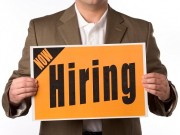 Businessman holding Now Hiring sign